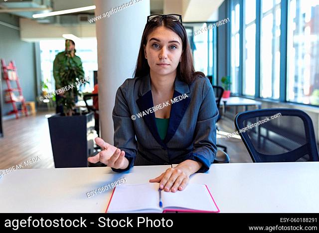 Portrait of caucasian female creative worker sitting at desk looking at camera