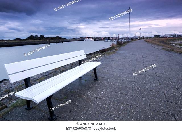 wide-angle view of the port of bensersiel in east frisia with white bench in the foreground at dusk
