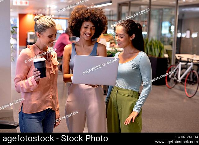 Happy multiracial female advisors discussing over laptop while working together at modern office