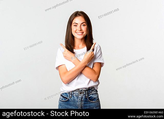 Cheerful attractive girl pointing fingers sideways, showing two variants