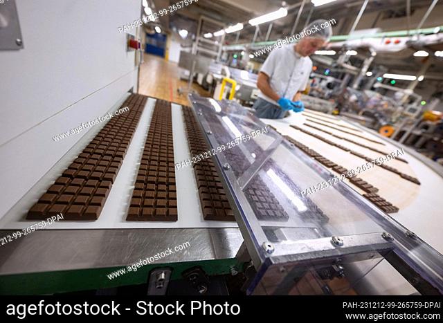 07 December 2023, Baden-Württemberg, Waldenbuch: Chocolate bars lie on a conveyor belt in production at the headquarters of Alfred Ritter GmbH & Co