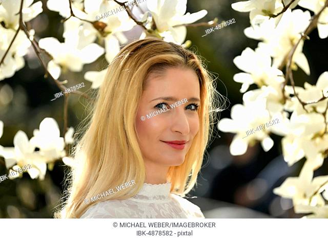 Blonde, portrait in front of a blooming magnolia tree, Baden-Württemberg, Germany