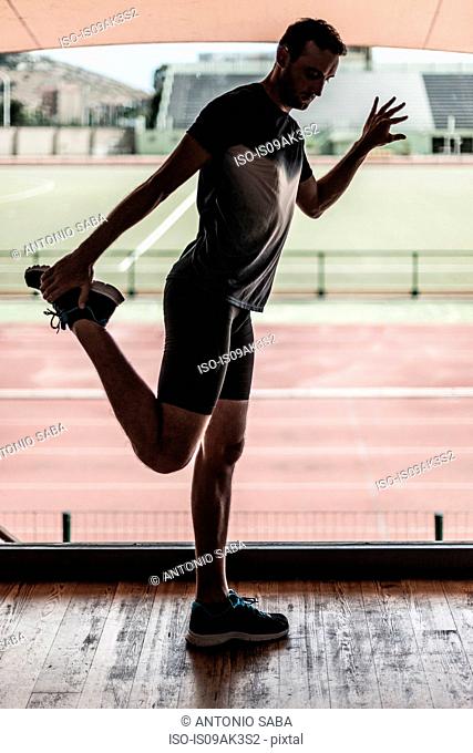 Mid adult man stretching leg muscles