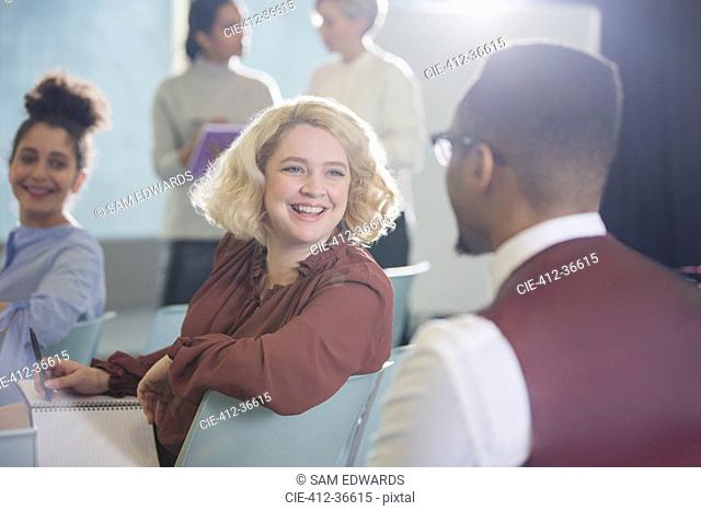 Smiling businesswoman turning and listening to businessman in conference audience