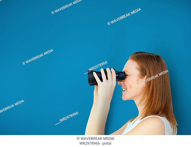 Happy woman looking through binoculars against blue background