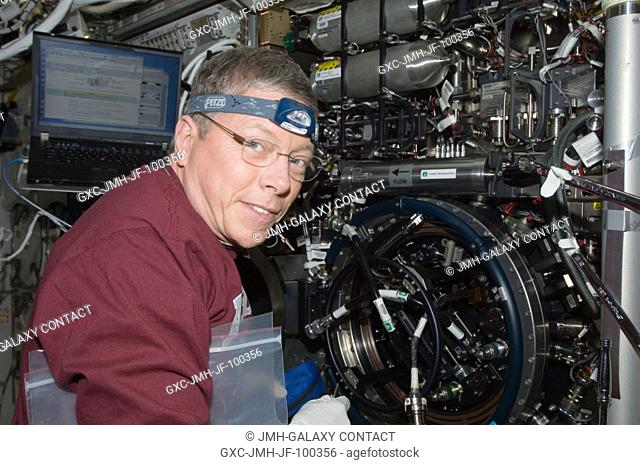 NASA astronaut Mike Fossum, Expedition 29 commander, works with the Combustion Integrated Rack (CIR) Multi-user Drop Combustion Apparatus (MDCA) in the Destiny...