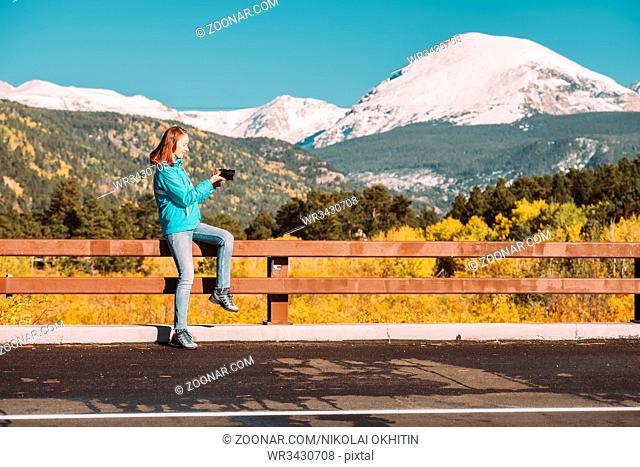 Woman tourist taking photo. Season changing from autumn to winter. Rocky Mountains, Colorado, USA