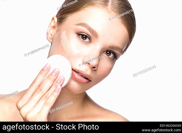 Beautiful young girl with sponge for application make-up and French manicure. Beauty face. Picture taken in the studio on a white background