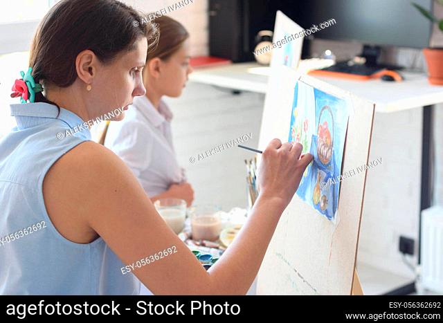 Girl sits next to the child and paints still life