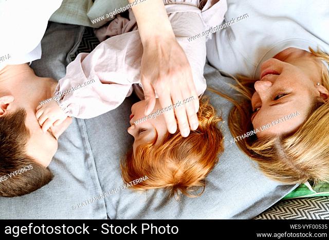 Daughter lying amidst mother and father on bed at home