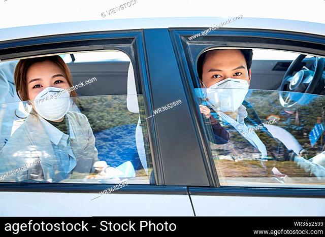 Young lovers wearing a mask by car