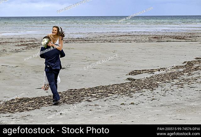 15 May 2020, Schleswig-Holstein, Stein: 23-year-old Lisann Camara and her husband Erik Camara are walking across the beach of the Kieler Foerde after their...