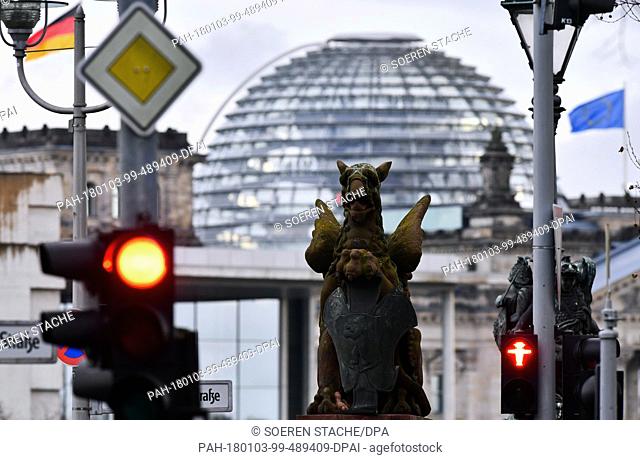 The dome of the Reichstag building towers over the stone griffin sculpture on the Moltkebridge in Berlin, Germany, 03 January 2018