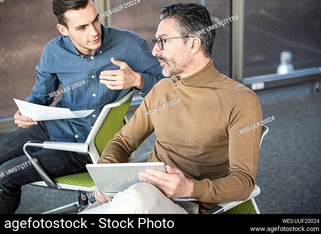 Mature businessman with tablet and young man working in office