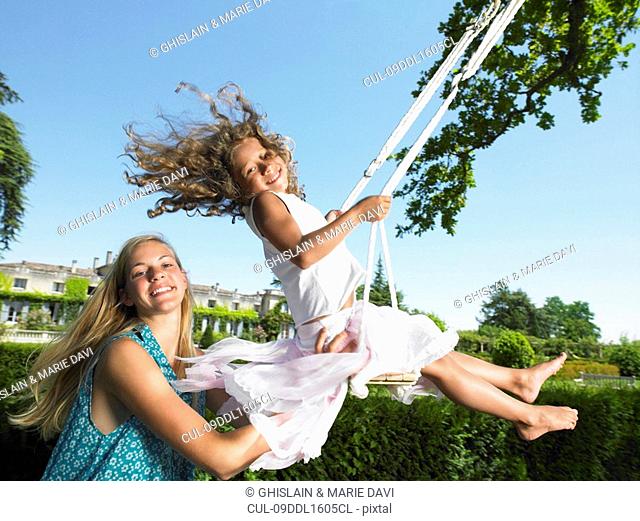 Girl on a swing, pushed by her sister