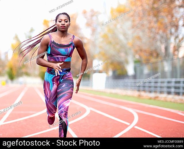 Young sportswoman wearing sports clothes running on track