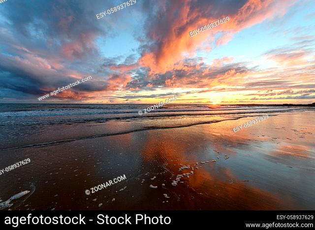 Sunset at the atlantic Ocean with orange beach and sky in France
