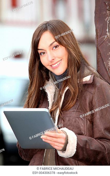 Young woman using electronic pad in town