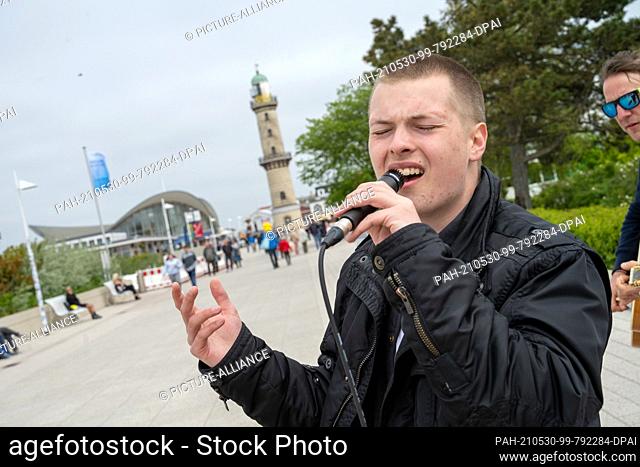 29 May 2021, Mecklenburg-Western Pomerania, Warnemünde: Musician Gabriel Kelly, son of Angelo Kelly (The Kelly Family), stands as a street musician on the beach...