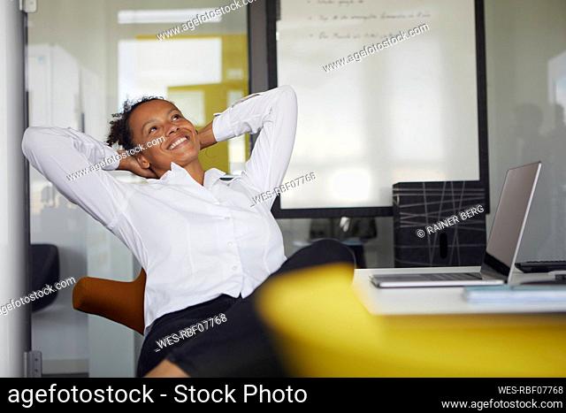 Portrait of happy businesswoman relaxing at desk in office