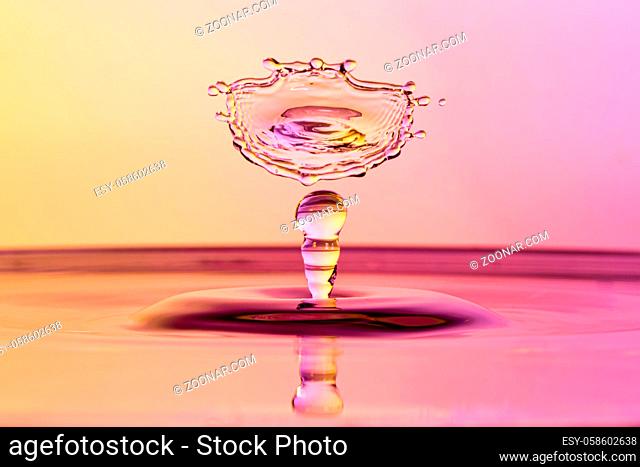 High speed water drop photograph with colliding drops in orange and purple colors