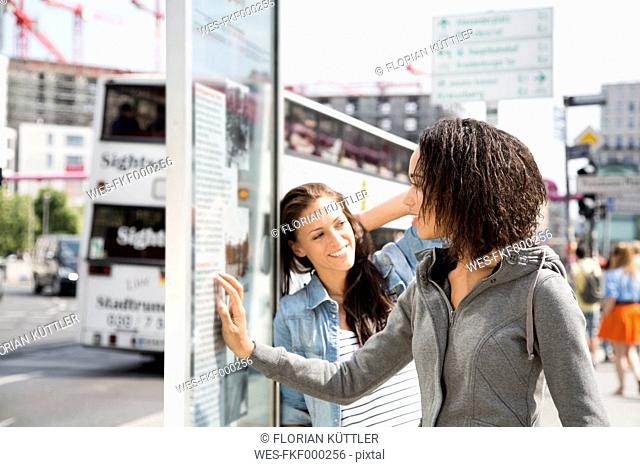 Germany, Berlin, Young women in the city, reading information panel