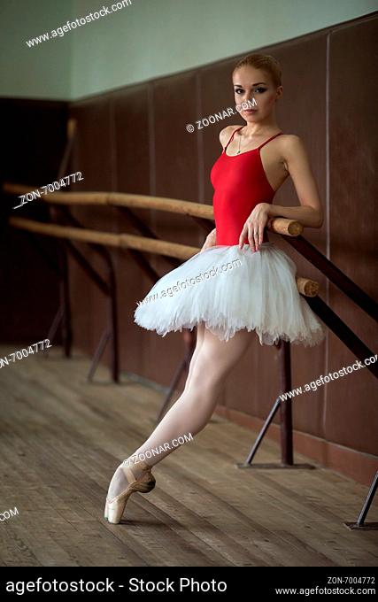 Ballerina standing near the bar on tiptoe, leaning his elbow