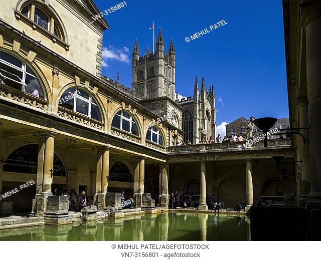 Visitors exploring the historic Roman Baths with Bath Abbey towering above, Bath, Somerset, England, UK. The Great Bath is the largest pool in the Roman Baths