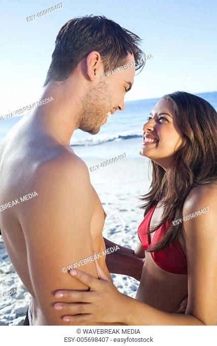 Cheerful cute couple in swimsuit holding one another