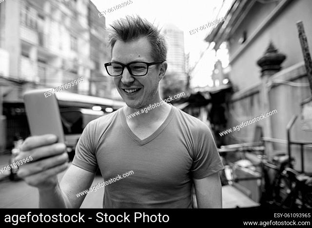 Portrait of young handsome tourist man exploring around the city streets in black and white
