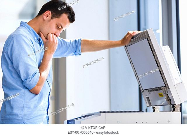 Handsome young man using a copy machine (shallow DOF color toned image)