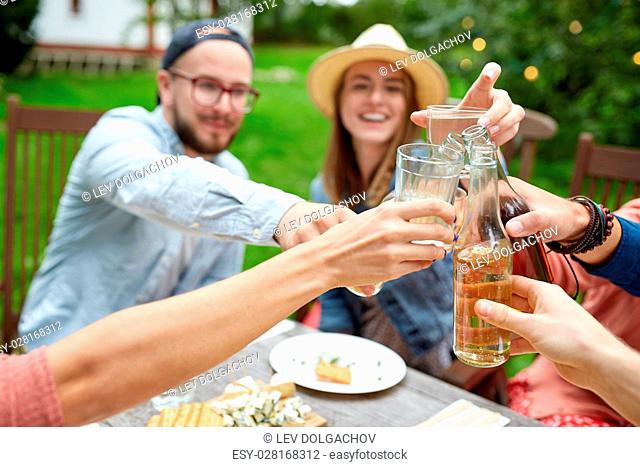 leisure, holidays, eating, people and food concept - happy friends having dinner at summer garden party and clinking drinks