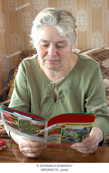 An elderly woman reading a magazine