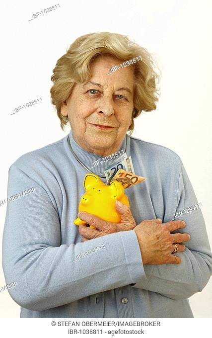 Old woman, 80 years old, holding a piggy bank