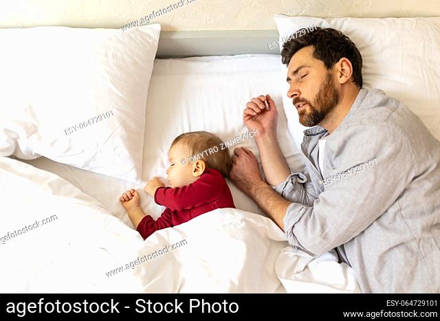 Father and little baby sleeping together in bed, parenthood, newborn daughter