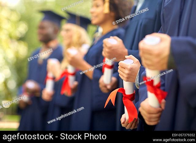 graduate students in mortar boards with diplomas