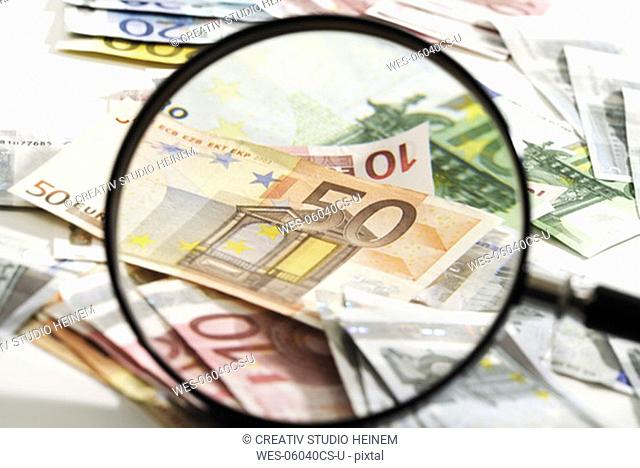 Euro banknotes under magnifying glass, close-up