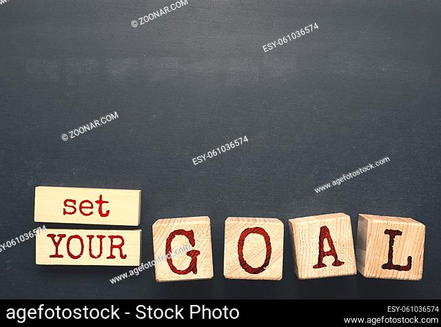 The words Set YOUR GOAL on wooden blocks on a blackboard with space for text or image