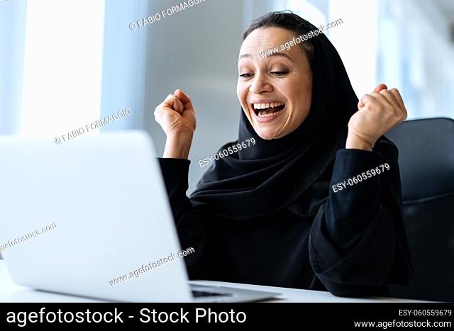 beautiful woman with abaya dress working on her computer. Middle aged female employee at work in a business office in Dubai