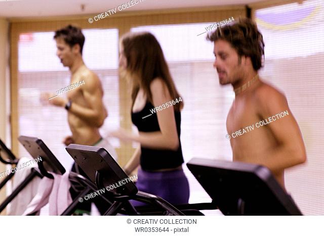 athletic youths running on treadmills at a gym