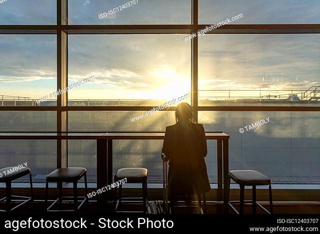 UK, London, Rear view of woman at airport terminal at sunset