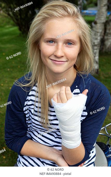 Teenage girl with bandage on hand, smiling, portrait