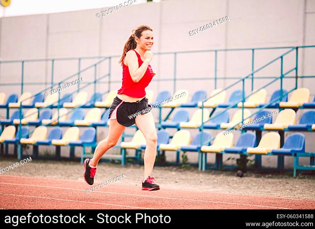 Woman Running At The Stadium. Young woman running during on stadium track. Goal achievement concept. Fitness Jogging Workout on ballpark