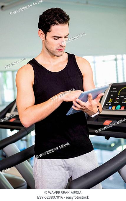 Serious man on treadmill standing with tablet
