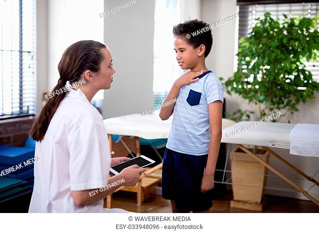Female therapist looking at boy touching neck