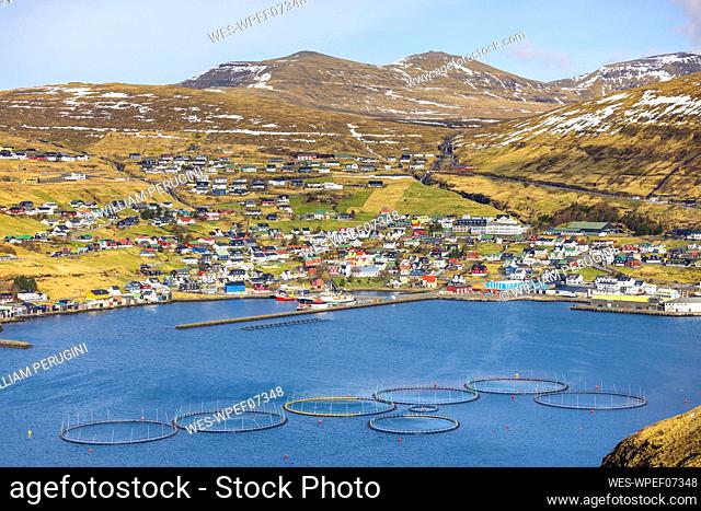 Salmon fish farm with townscape and mountains in Vestmanna, Faroe Islands
