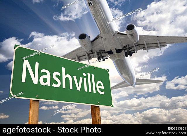Nashville green road sign and airplane above with dramatic blue sky and clouds