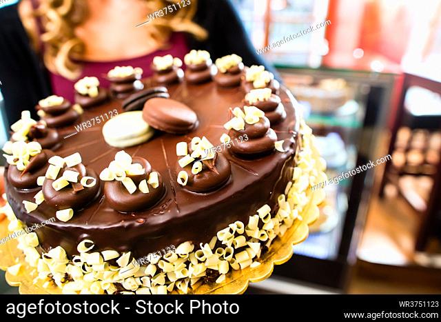Female confectioner presenting tray of cake in bakery or pastry shop