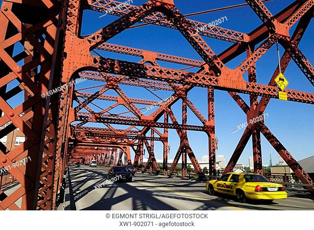 yellow cab and cars crossing a historic steel bridge over Willamette River, Portland, Oregon, USA