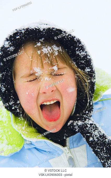 Girl catching snowflakes with her tongue